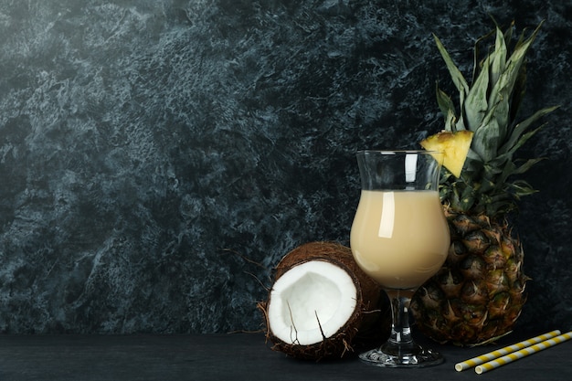 Coquetel e ingredientes Pina Colada contra um fundo de fumaça preta.