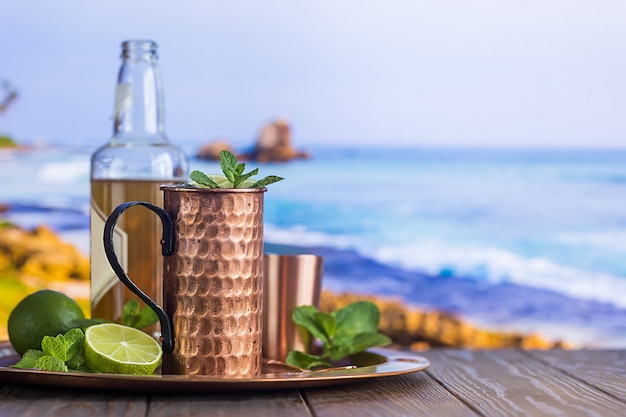 Coquetel gelado Moscow Mules com cerveja de gengibre, vodka e limão na praia e à beira-mar