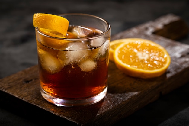 Coquetel negroni com laranja em fundo escuro