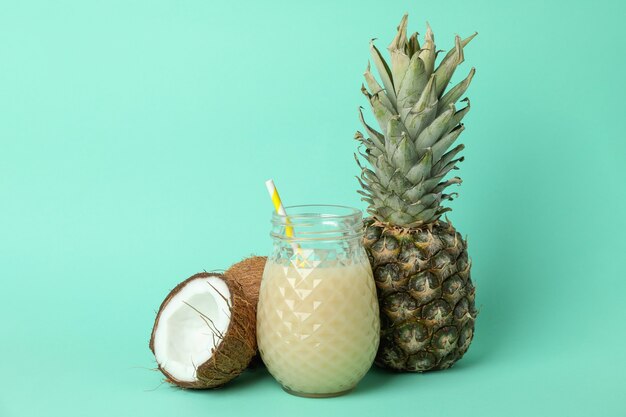 Coquetel Pina Colada e ingredientes em fundo de hortelã.