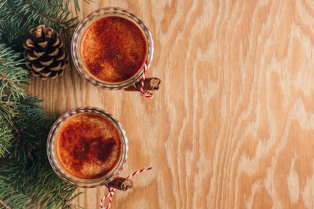 Coquetel tradicional de leite de Natal Gemada com canela servida em dois copos na mesa de madeira festiva Vista superior com espaço para cópia