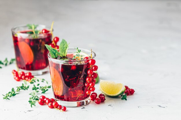 Coquetel vermelho frio com passas, menta, tomilho e gelo em copo em mesa de concreto cinza claro Bebidas de verão e coquetels alcoólicos Coquetel alcoólico Mojito de passas