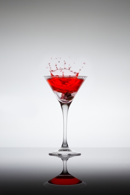 Foto coquetel vermelho respingando em uma taça de martini