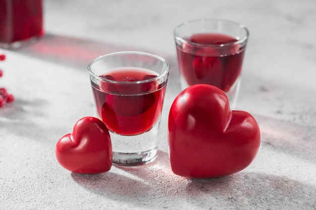 Coquetel vermelho, vodka ou licor e decorações em forma de coração em fundo branco. Feliz dia dos namorados conceito.