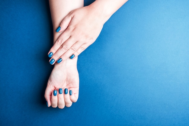 Cor azul elegante de manicure de mulheres bonitas. O conceito de tons de inverno para unhas, auto-cuidado. Espaço para texto