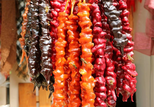 Cor vibrante deliciosa churchkhela, doces tradicionais georgianos à venda atraindo muitas abelhas