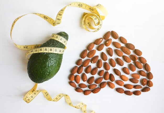 Coração de amêndoa e abacate com fita métrica Dieta para perda de peso Amoroso estilo de vida saudável Conceito vegan Nutrição adequada Comida esportiva Nozes e vitaminas