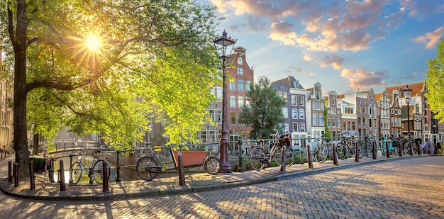 Coração de amsterdã manhã cedo em amsterdã casas antigas uma ponte bicicletas tradicionais canais e o sol brilha por entre as árvores ótimo dia em amsterdã