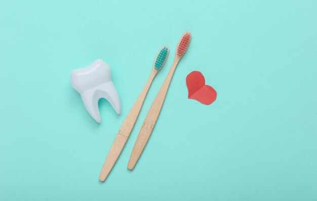 Coração de bambu ecológico e escova de dentes e dente em fundo rosa Love Dental care conceptxATop view