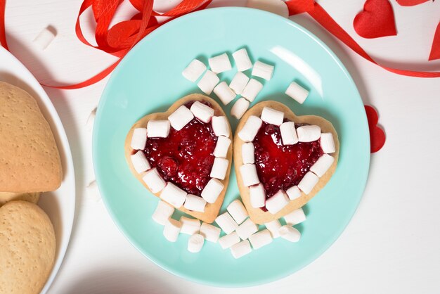 Coração de biscoito decorado com geléia e marshmallows para o dia dos namorados, close-up, assando para o feriado. vista superior dos corações decorativos.