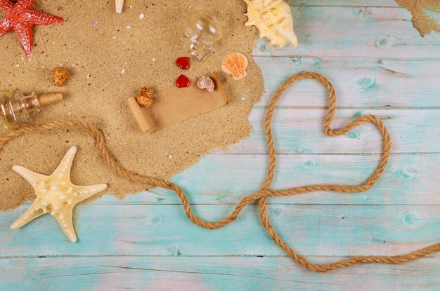 Coração de corda náutica na costa do oceano com conchas e estrelas do mar