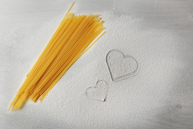 Coração de farinha e macarrão em fundo cinza