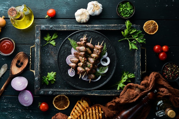 Coração de frango assado em espetos em um prato preto carne de frango vista superior espaço livre para o seu texto