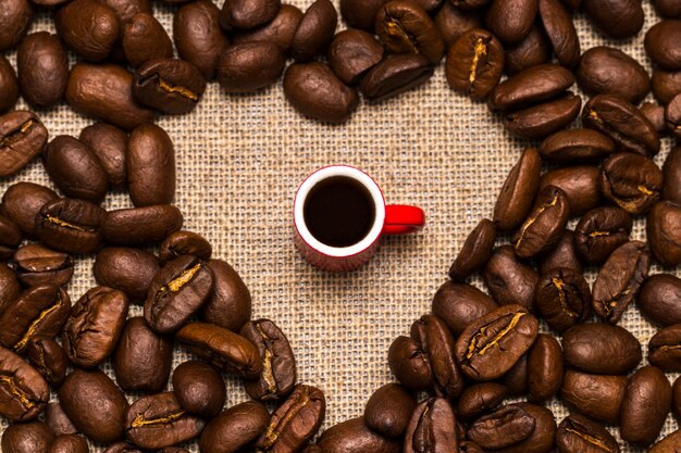 Coração de grãos de café e uma xícara na serapilheira