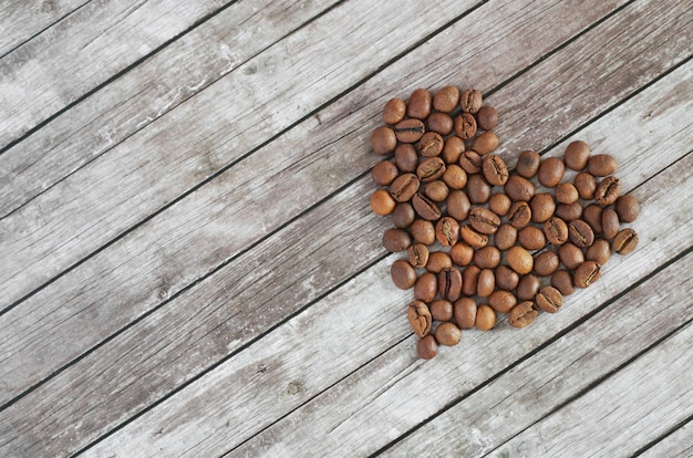 Coração de grãos de café em um fundo de madeira