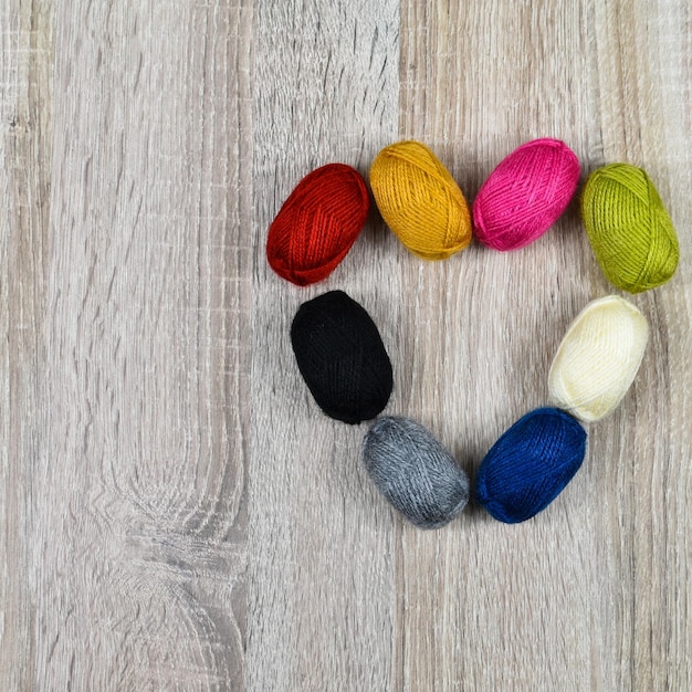 Coração de meadas coloridas de fios para tricô em um fundo de madeira