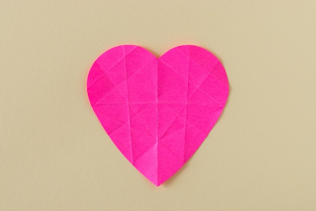 Coração de papel rosa amassado em um fundo brilhante