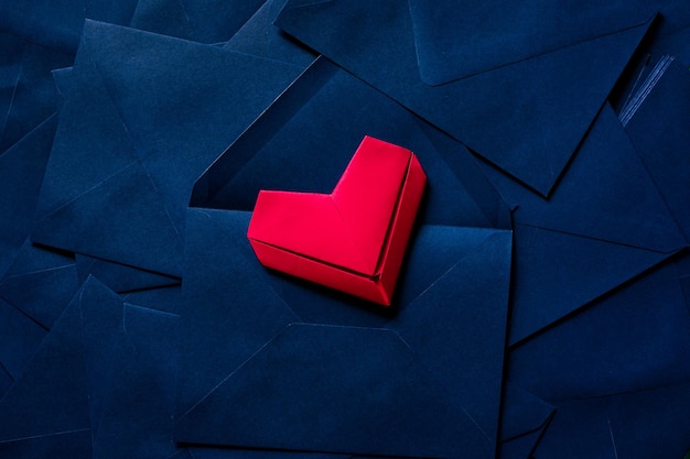 coração de papel vermelho e envelope azul, ideia de carta de amor com envelope azul com corações vermelhos derramando.