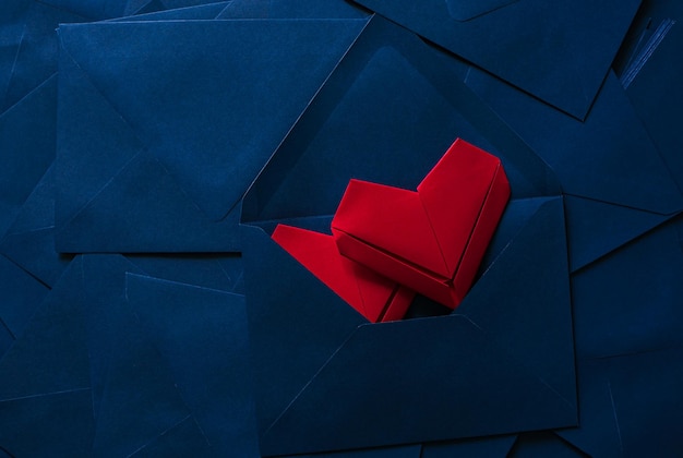 coração de papel vermelho e envelope azul, ideia de carta de amor com envelope azul com corações vermelhos derramando.