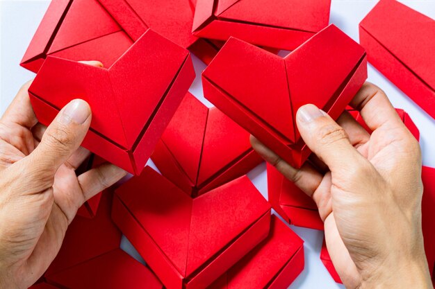 coração de papelMãos segurando o coração de origami dobrado fundo branco garotinhos mão segurando um coração vermelho