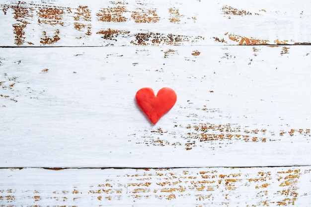 Foto coração de plasticina vermelha em fundo branco de madeira.