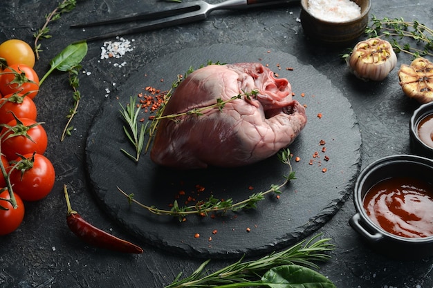 Coração de porco cru está pronto para cozinhar com especiarias e ervas Carne em um fundo preto