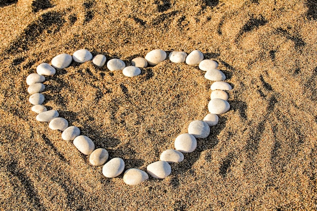 Coração de seixos incrustados na areia