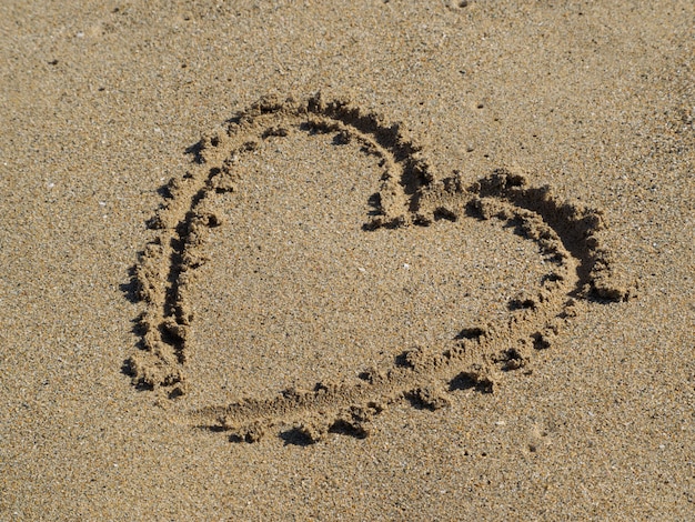 Foto coração, desenhando um dedo na areia.