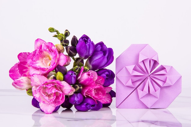 Coração dos namorados de origami e buquê rosa e roxo em fundo branco