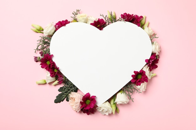 Coração em branco e flores diferentes em fundo rosa, espaço para texto