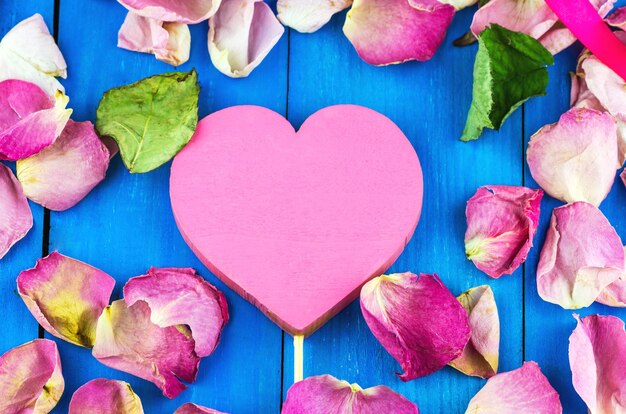 Coração em uma vara entre pétalas de rosa brilhantes
