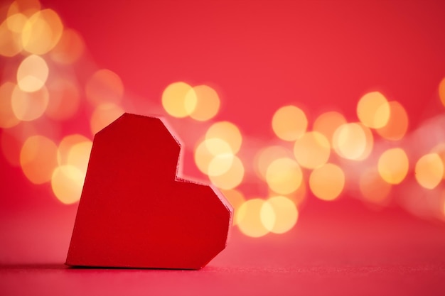 Foto coração feito à mão de papel vermelho sobre fundo vermelho com boke festivo cartão criativo para o dia de são valentim