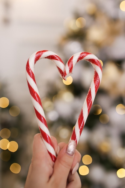 Coração feito de bastões de doces de natal em um fundo de bokeh e guirlandas