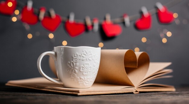 Coração feito de folhas de livro com um copo de luzes, conceito de amor e dia dos namorados em uma mesa de madeira