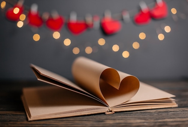 Coração feito de folhas de livro no conceito de luzes, amor e dia dos namorados em uma mesa de madeira