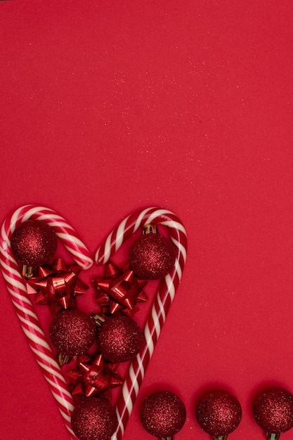 Coração flatlay de natal forrado com pirulitos de natal e decorado com brinquedos de árvore de natal.