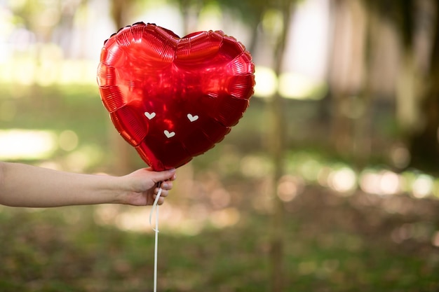 Coração inflável na cor vermelha no fundo da floresta Conceito de cartão de férias de amor feliz dia dos namorados no ar