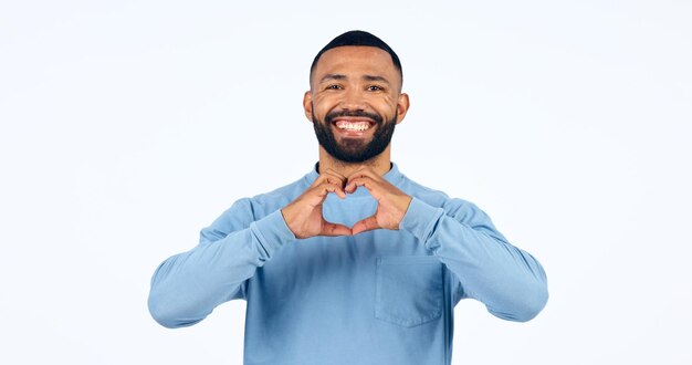 Coração, mãos e retrato de um homem em estúdio por bondade, ícone feliz e doação de caridade em fundo branco, sorriso, amor e emoji, sinal de esperança, bem-estar e obrigado pelo apoio, cuidado e paz.