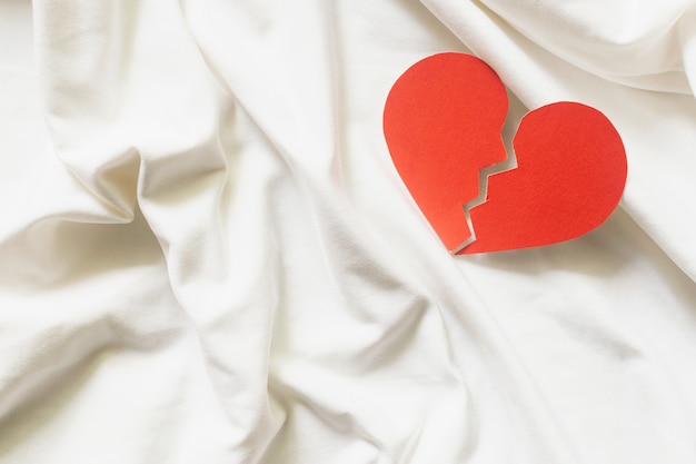 Coração partido vermelho em têxteis brancos. conceito de divórcio.