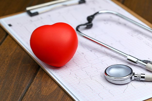 Coração vermelho com estetoscópio e eletrocardiograma em fundo de madeira