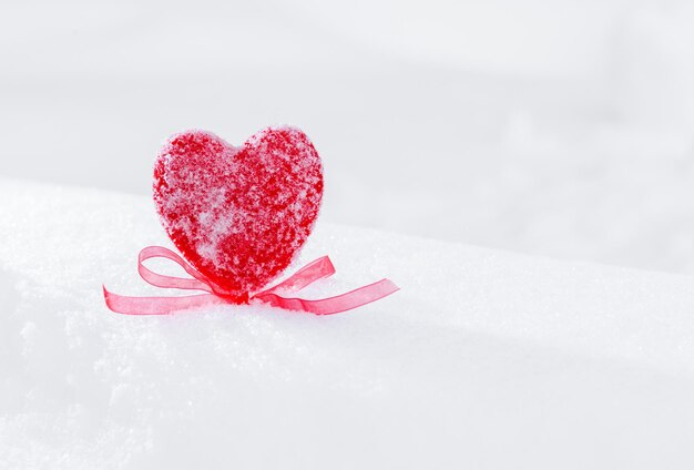 Coração vermelho com um laço na neve.