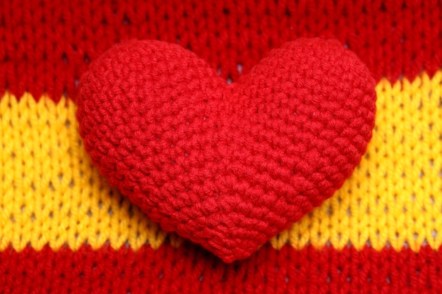 Coração vermelho de malha encontra-se em um fundo de malha vermelho-amarelo. foto de alta qualidade