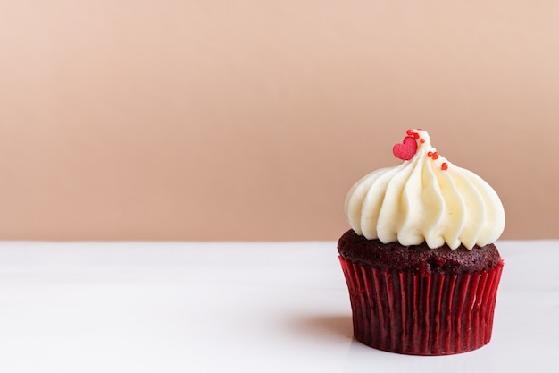 Coração vermelho doce em cupcake creme branco