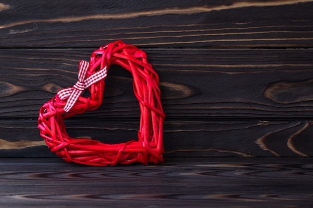 Coração vermelho sobre fundo escuro de madeira. textura de placas marrons. cartão de presente de dia dos namorados. símbolo do amor, conceito romântico. quadro de férias em estilo lacônico, minimalismo.