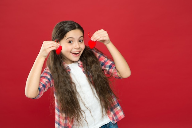 Corações cheios de amor Criança feliz com coração decorativo vermelho Amor e família Felicidade da infância Feriado de fevereiro Dia das crianças menina feliz Dia dos namorados Menina pequena com olhar fofo