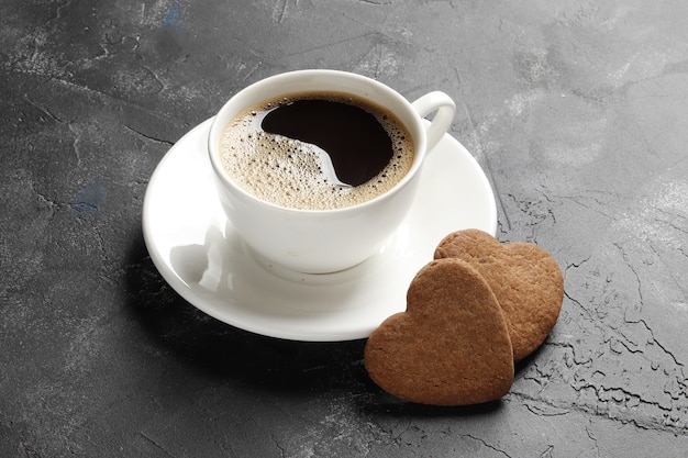 Corações de deliciosos biscoitos caseiros com uma xícara de café em um fundo escuro. Vista do topo. Lugar para texto.