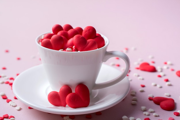 Corações de doces de açúcar doce vermelho em uma xícara de café. Conceito de amor e dia dos namorados. Fundo festivo