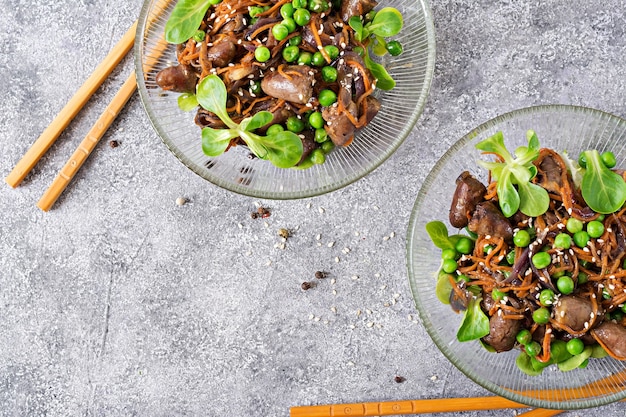 Corações de frango com cenouras, cebolas e ervilhas verdes em estilo asiático. Vista do topo