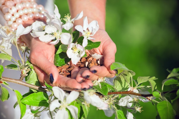 Corações de madeira amam as mãos de mulher atrás de uma macieira de flor. Conceito de paz e harmonia. segurando o símbolo do amor de forma de coração para o feriado do dia dos namorados. conceito de estilo de vida e sentimentos de saudação romântica