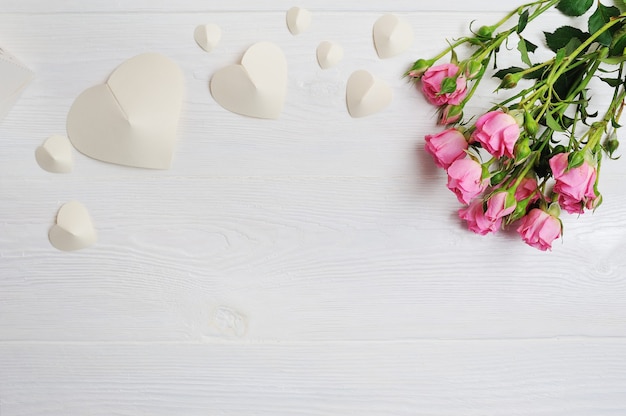 Corações de origami branco de maquete de papel com rosas cor de rosa, cartão de dia dos namorados. camada plana, vista superior